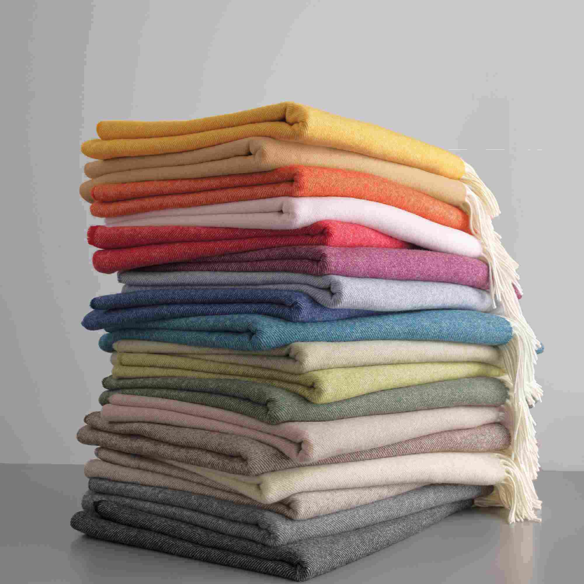 Deckenstapel mit bunten Merino-Wolldecken mit Fransen