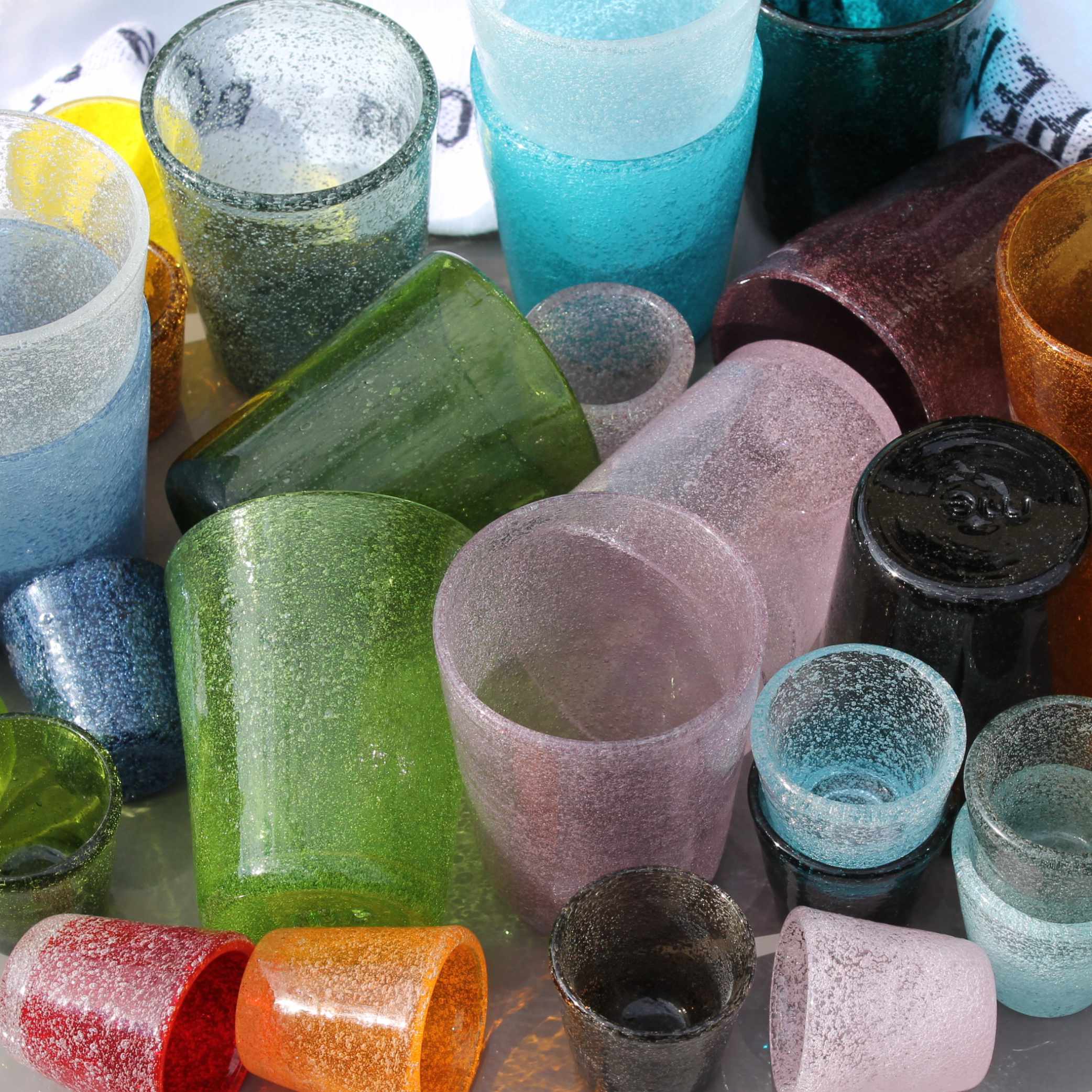 bunte-mundgeblasene Gläser durcheinandergewürfelt auf einem Tisch