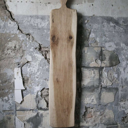 Tapasbrett aus Eiche 95 cm lang, mit sichtbaren Astlöchern aus einem Stück geschnitten, Laura living. Abgebildet vor einer rustikalen alten Fliesenwand.